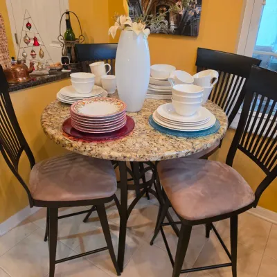 Sale Photo Thumbnail #51: Round granite-top pub table with a metal base, paired with four black slat-back high-top chairs featuring upholstered seats.