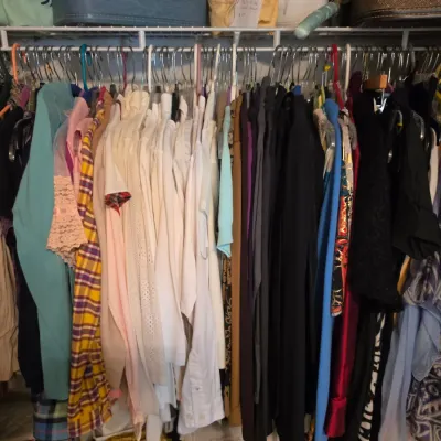 Sale Photo Thumbnail #199: Closet rack packed with vintage and contemporary women's clothing, including blouses, dresses, and pants in various patterns and colors.
