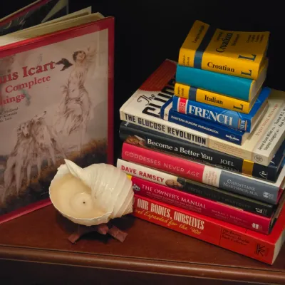 Sale Photo Thumbnail #221: Collection of hardcover art, language, and self-help books displayed next to a seashell candle holder.