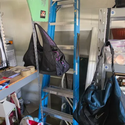 Sale Photo Thumbnail #295: Black Adidas duffel bag with purple accents and a blue Nike duffel bag hanging in a garage storage area beside a blue fiberglass stepladder.