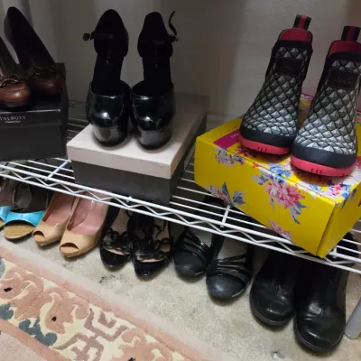 Sale Photo Thumbnail #151: Collection of women's shoes on a wire storage rack, featuring pumps, platform heels, flats, and Joules patterned rain boots with original boxes.