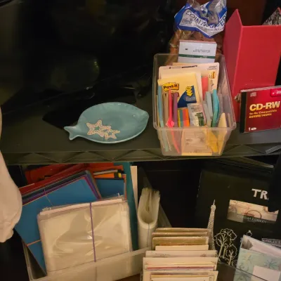 Sale Photo Thumbnail #253: Collection of office and craft supplies including sticky notes, binders, plastic storage bins, photo sleeves, and a small fish-shaped ceramic dish.