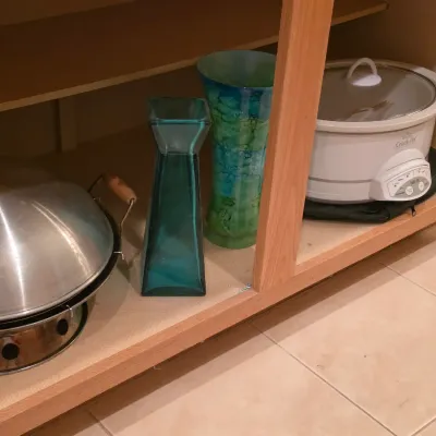 Sale Photo Thumbnail #28: Selection of kitchenware and decor items stored in a cabinet, including a Rival Crock-Pot, two glass vases, and a metal chafing dish or fondue set.