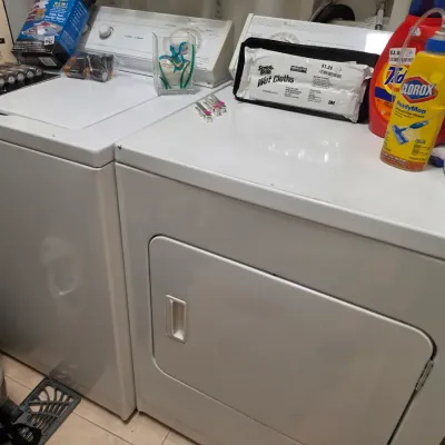 Sale Photo Thumbnail #267: White top-loading washing machine and matching electric dryer set, accompanied by various laundry supplies and household items.