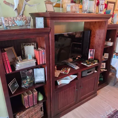 Sale Photo Thumbnail #84: Large wooden entertainment center with flanking bookcases, housing decor, books, and a flat-screen television.