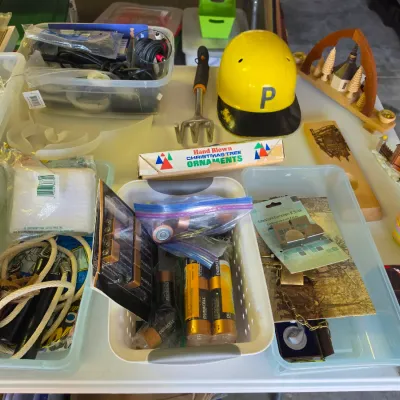 Sale Photo Thumbnail #317: Collection of eclectic household items including plastic organizer tubs filled with hardware, batteries, ropes, a novelty yellow Pittsburgh Pirates helmet, and hand-blown Christmas ornaments.