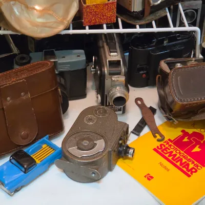Sale Photo Thumbnail #208: Collection of vintage cameras, leather equipment cases, an 8mm movie camera, a blue toy truck, and a Kodak Photographic Seminar booklet.