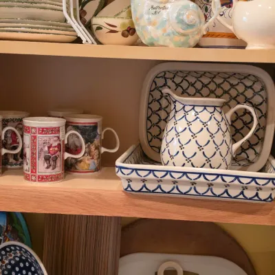 Sale Photo Thumbnail #35: Collection of kitchenware and ceramics including Polish pottery serving pieces and Santa Claus themed mugs inside a wooden cabinet.