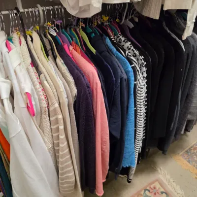 Sale Photo Thumbnail #159: Closet rack packed with a varied collection of women's contemporary clothing, including sweaters, cardigans, blouses, and jackets in various colors and patterns.