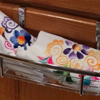 Sale Photo Thumbnail #64: Hand-embroidered white linen towels with colorful floral designs stored in an over-the-cabinet chrome rack.