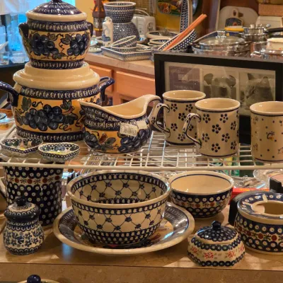 Sale Photo Thumbnail #2: Collection of Polish pottery Boleslawiec stoneware featuring various floral, peacock, and grape patterns, including bowls, mugs, a teapot, and a gravy boat.