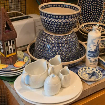 Sale Photo Thumbnail #37: Collection of Polish pottery nesting bowls and serving dishes displayed alongside white porcelain creamers, a Delftware bottle, and decorative ceramics.
