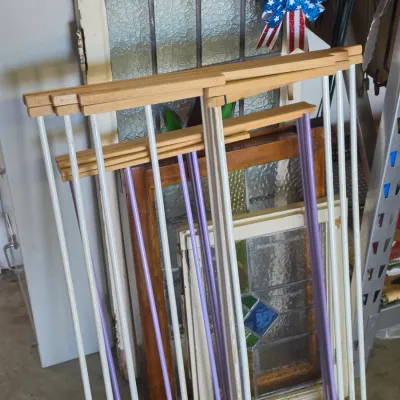Sale Photo Thumbnail #286: Collection of wooden window chimes and framed stained-glass window panes stored together.