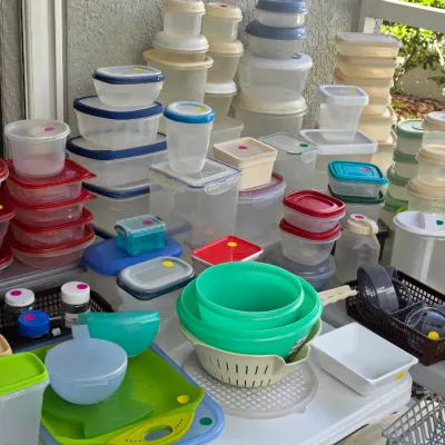 Sale Photo Thumbnail #321: Large collection of plastic food storage containers, Tupperware, nesting bowls, and kitchen accessories arranged on folding tables.