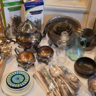 Sale Photo Thumbnail #62: Collection of metalware and kitchen items, including a tarnished silver-plated tea set, packaged flatware, glass cruets, metal bowls, and Progressive herb keepers.