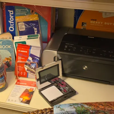 Sale Photo Thumbnail #237: Canon PIXMA photo printer arranged with assorted office supplies, Canon photo paper, a vintage children's religious book, and a Yankee Candle.
