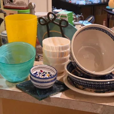 Sale Photo Thumbnail #5: Collection of decorative kitchenware and glassware, featuring Polish pottery nesting bowls, swirl-pattern art glass bowls, alabaster bowls, and a bright yellow vase.