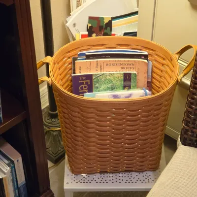Sale Photo Thumbnail #246: Large woven split-wood basket with double leather side handles, filled with various books and pamphlets.