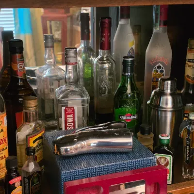 Sale Photo Thumbnail #74: Collection of assorted liquor bottles and barware accessories arranged inside a wooden cabinet.