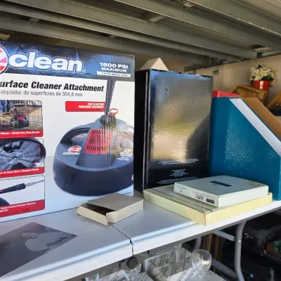 Sale Photo Thumbnail #311: EZ Clean 12-inch surface cleaner attachment in original box, displayed alongside desk organizers and miscellaneous household items on a folding table.