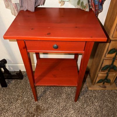Sale Photo Thumbnail #111: Red-painted wooden nightstand or side table featuring a single drawer with a dark metal pull knob and a lower display shelf.