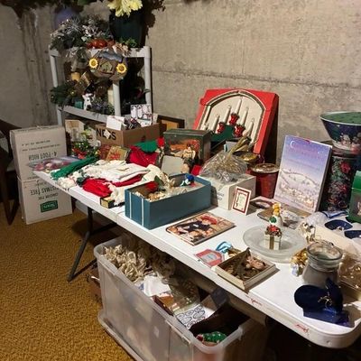 Sale Photo Thumbnail #8: Folding table displaying vintage Christmas decor, including boxed candelabras, linens, ornaments, and holiday tins.