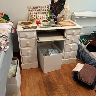 Sale Photo Thumbnail #11: White wooden student desk with drop-down keyboard tray, side drawers, and various small home decor items on top.