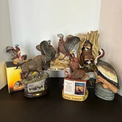 Collection of vintage Wild Turkey ceramic decanters and wildlife figurines, featuring turkeys, bison, raccoons, and a pelican.