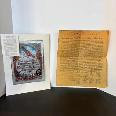 Framed illuminated Pledge of Allegiance print with informational card alongside an aged parchment reproduction of the Declaration of...