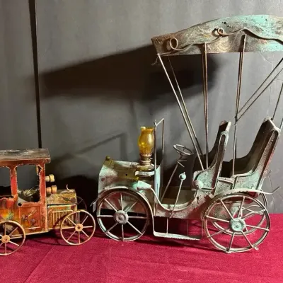 Two vintage metallic novelty car models, including a large painted verdigris-style automobile with a carriage canopy and small amber...