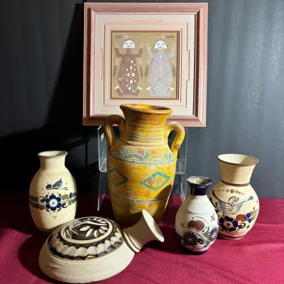 Collection of southwestern and Mexican pottery vessels paired with a framed sand painting featuring Yeii figures.