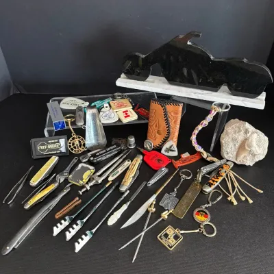 Eclectic assortment of vintage small collectibles including pocket knives, keychains, glass-cutting tools, a leather pouch, and a...