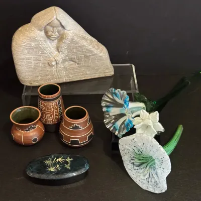 Collection of decorative items including a carved stone Indigenous figure, three small geometric pottery vessels, hand-blown glass...