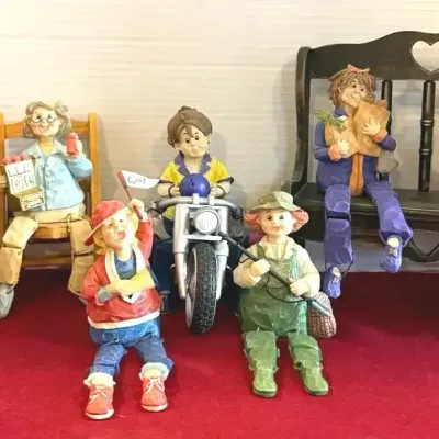 Collection of carved-look resin shelf-sitter figurines depicting whimsical characters engaged in various activities, seated on miniature...