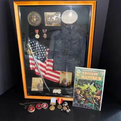 Military memorabilia shadow box display featuring USMC uniform items, medals, flag, sword, and hat, paired with loose military pins and a...