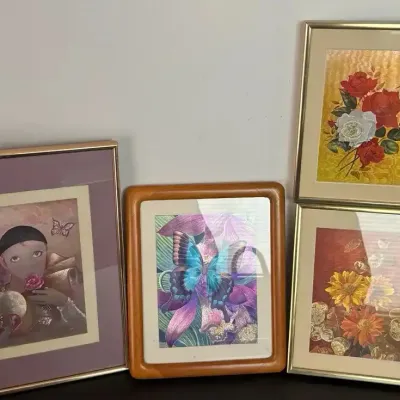 Collection of four framed vintage artworks, including floral prints and a pierrot figure, housed in metal and wooden frames.