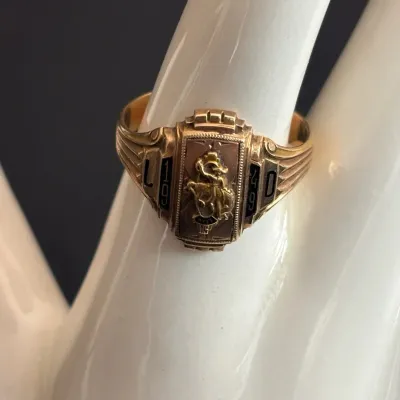 Vintage 1949 high school class ring featuring a gold crest setting with black enamel detailing on a display hand.