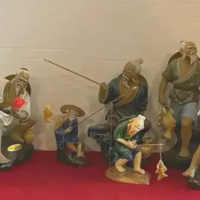Collection of seven vintage Shiwan mudman ceramic figurines depicting traditional Chinese fishermen with fishing poles and catch.