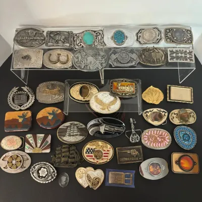 Large collection of vintage belt buckles featuring Western, Harley-Davidson, wildlife, patriotic, and stone-inlaid designs.