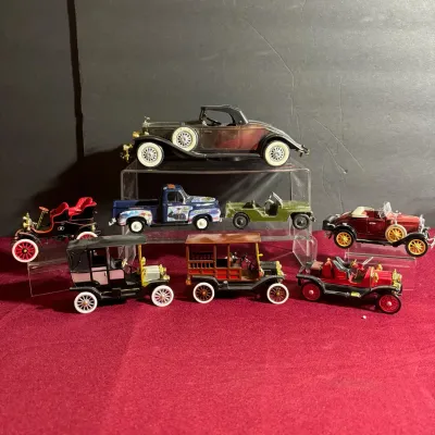 Collection of vintage die-cast model cars and trucks displayed on clear acrylic stands, featuring classic early 20th-century vehicle...