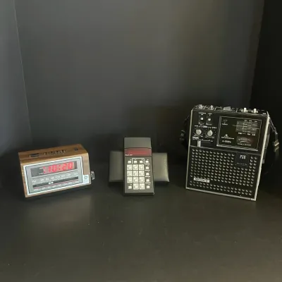 Sale Photo Thumbnail #102: Collection of vintage electronics, including a GE woodgrain digital alarm clock radio, a Sinclair handheld calculator in case, and a Sony ICF-5500W portable multi-band radio.