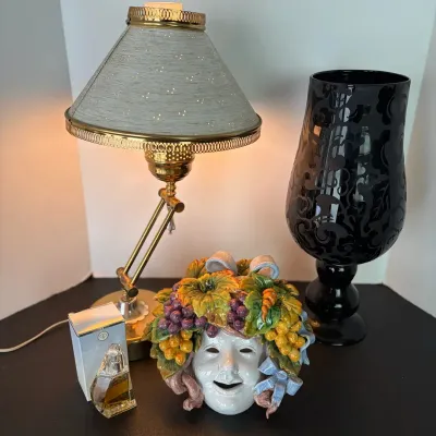 Vintage brass adjustable desk lamp with a light blue shade, alongside a black damask hurricane glass vase, an Italian ceramic theatrical...