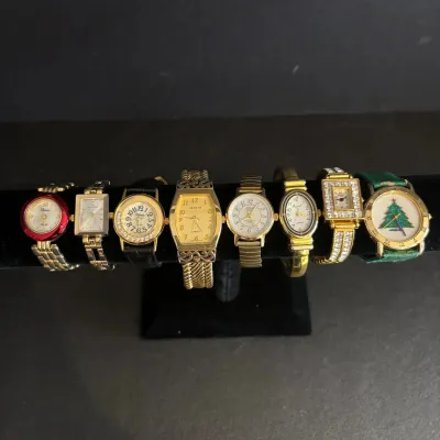 Collection of eight vintage women's quartz fashion wristwatches displayed on a T-bar jewelry stand, featuring various gold-tone,...