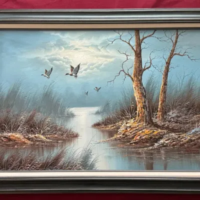 Framed oil painting depicting ducks flying over a misty marshland landscape, set in a dark wood frame with a cream liner, circa late 20th...