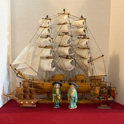 Vintage nautical decor collection featuring a large wooden model tall ship with cloth sails, flanked by two small model ships and a pair...