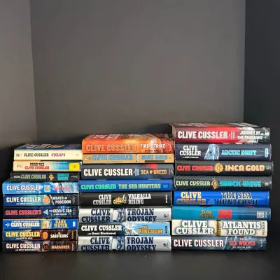 Collection of over twenty Clive Cussler hardcover and paperback adventure novel books.