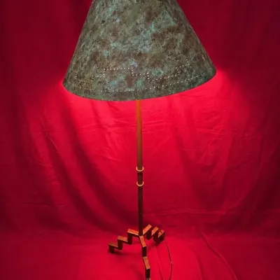 Southwestern-style metal floor lamp featuring a geometric step-motif tripod base and a perforated shade.