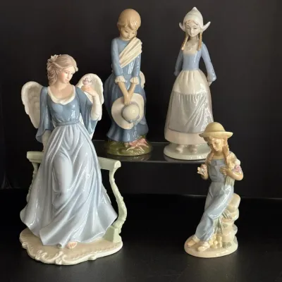 Collection of four porcelain figurines in pastel blue and white, including an angel and young women in traditional attire.