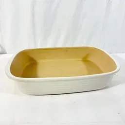 Sale Photo Thumbnail #211: Rectangular stoneware baking dish with a cream exterior and tan glazed interior, in good condition.