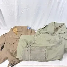Sale Photo Thumbnail #181: Vintage military clothing surplus, including tan and olive drab field jackets and trousers.